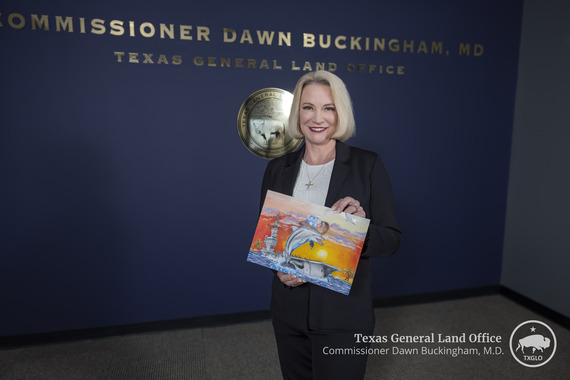 Commissioner Buckingham proudly shows off the winning entry for the 29th Annual Treasures of the Texas Coast Children's Art Contest.