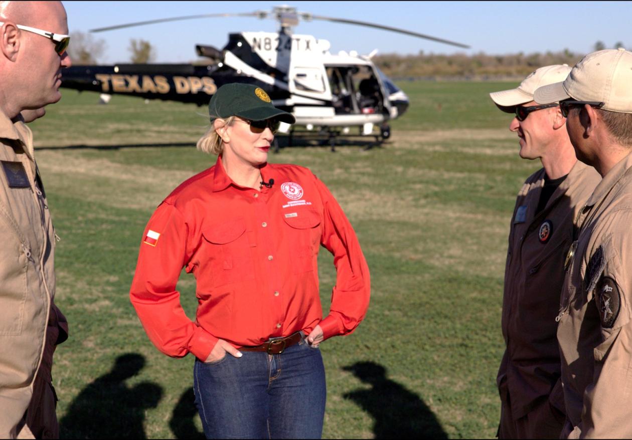 Commissioner Dawn Buckingham, M.D. talking to Border Patrol agents in front of a helicopter