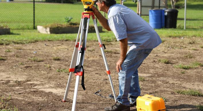 Man looking through a land surveying instrument.