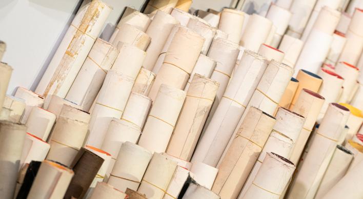 Many rolled up maps stacked vertically against the wall.