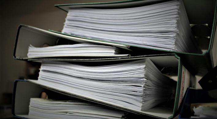 4 binders stacked on top of one another full of paper.