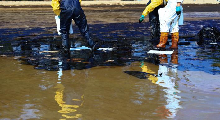 2 men wade in an oil spill in the ocean