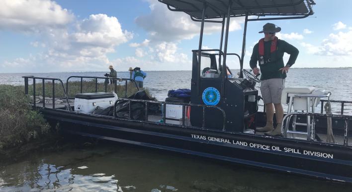 TX GLO Oil Spill boat by shore with people cleaning the coast.
