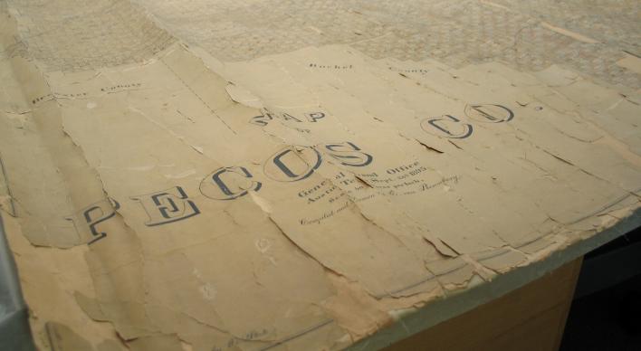 Bottom left corner of an original map with tattered edges with Pecos Co written in a vintage font