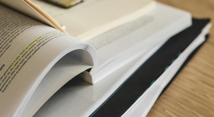 Close up of a stack of open books and notes on a desk.